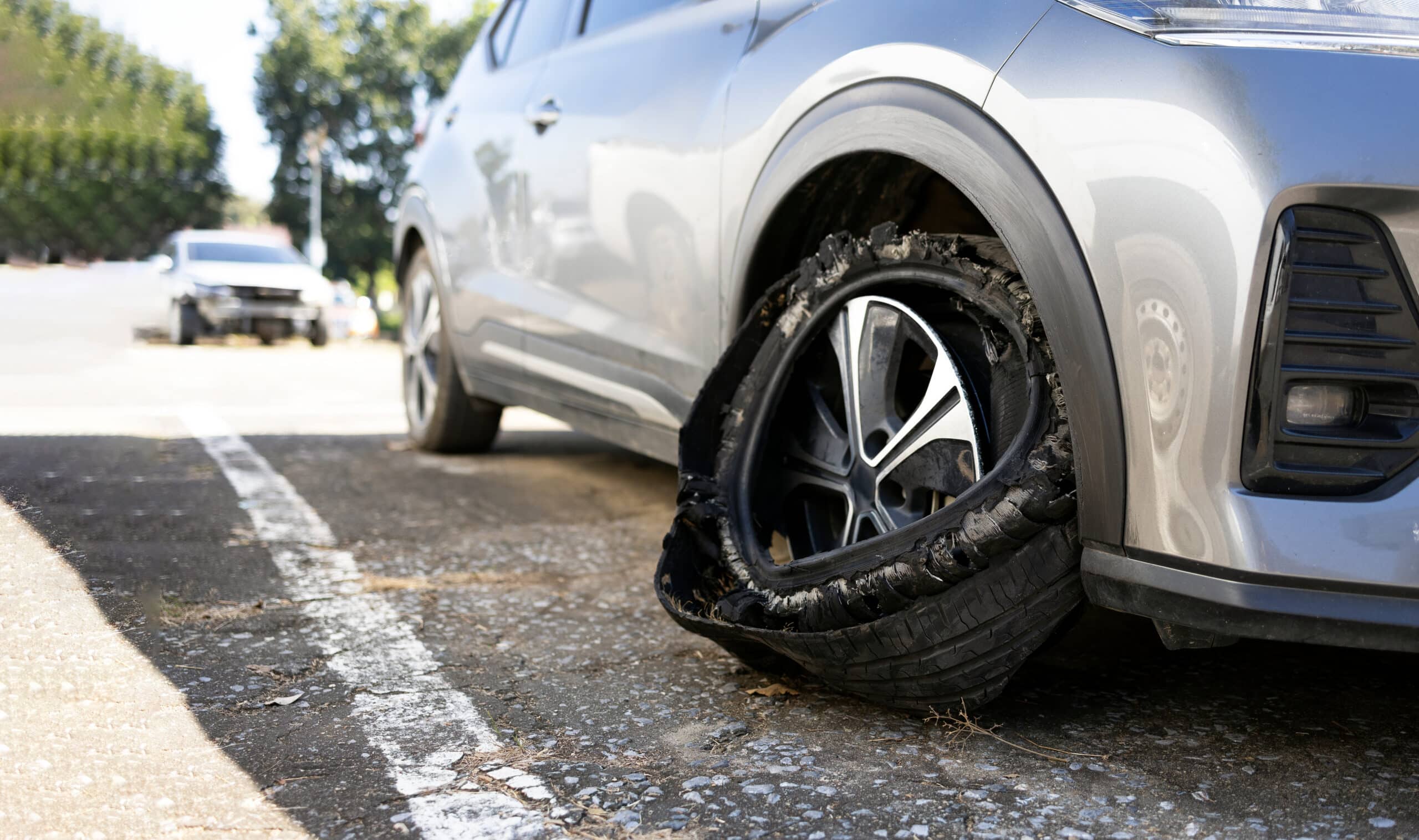 A car has experienced a tire blowout and is pulled over on the side of the road