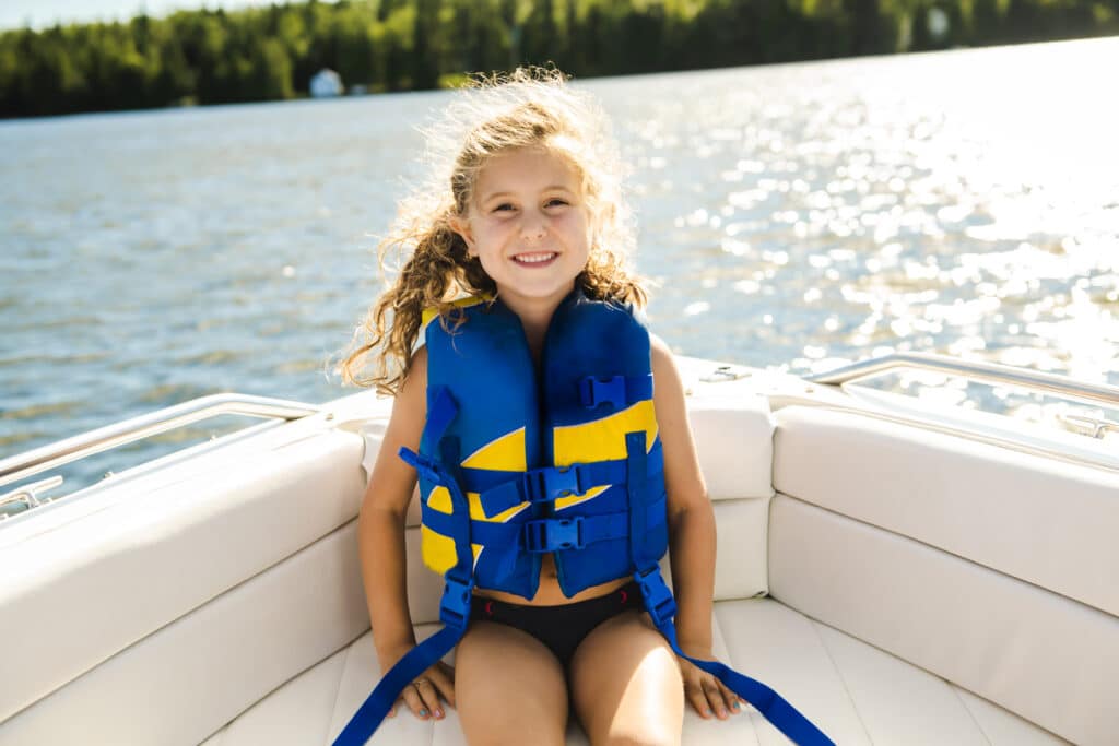 Little girl on a boat wearing a life jacket.