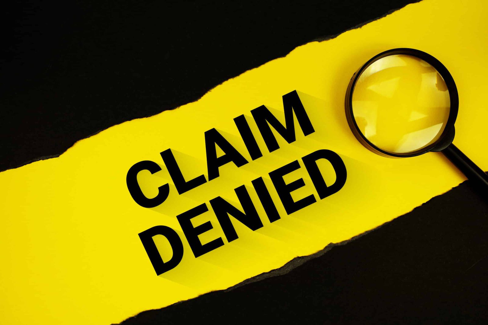 Claim Denied text on yellow with black paper torn ripped and magnifying glass