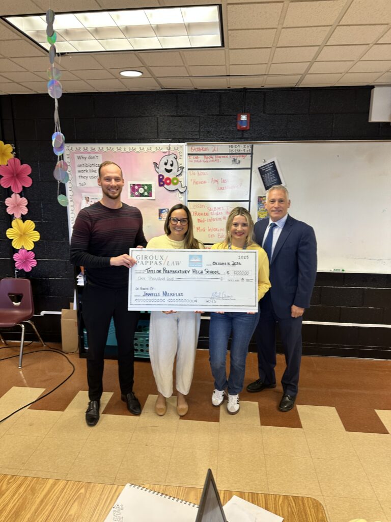 Group of four people holding a large check in a school setting.